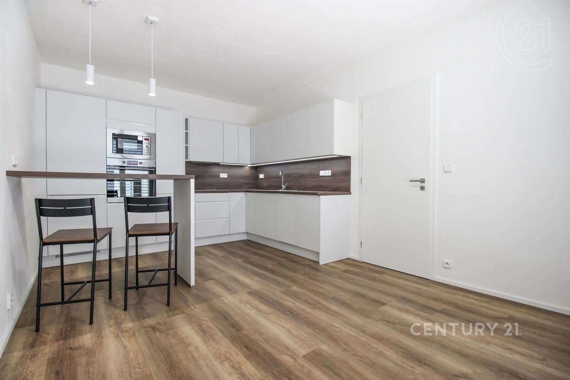 kuchyně s backsplash, ploché panelové skříňky, mikrovlnná trouba, dřevěná podlaha, a bílé skříně