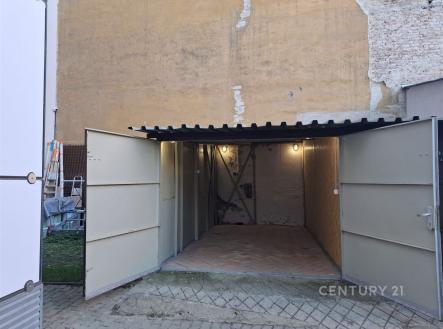 Prázdná garáž s dřevěnou podlahou a betonovými stěnami, jednoduchá konstrukce, vhodná pro parkování nebo uskladnění věcí. | Pronájem - malý objekt/garáž