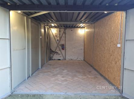 Jednoduchá garáž s průmyslovým stropem, dlážděnou podlahou a dřevěnými obklady, vhodná pro uskladnění nebo parkování vozu. | Pronájem - malý objekt/garáž