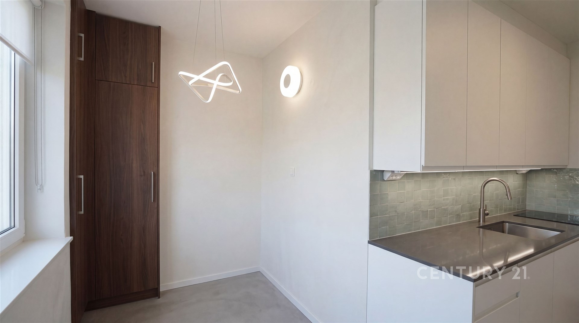 Moderní kuchyň s vestavěnými skříněmi, dlažbou a bílými skříňkami, vybavená elegantním osvětlením a nerezovým dřezem.