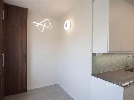 Moderní kuchyň s vestavěnými skříněmi, dlažbou a bílými skříňkami, vybavená elegantním osvětlením a nerezovým dřezem. | Prodej bytu, 3+1, 75 m²