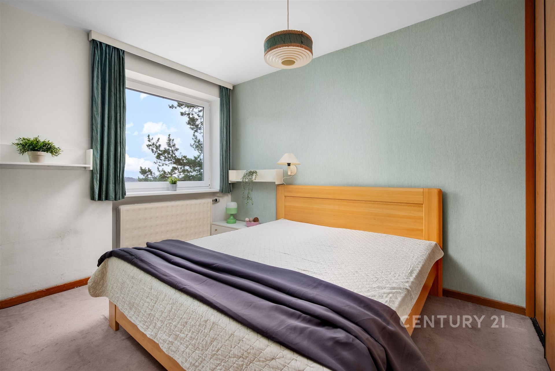 Světlá ložnice s parketovou podlahou, velkým oknem a vestavěnými skříněmi, moderní design a příjemná atmosféra pro relaxaci.