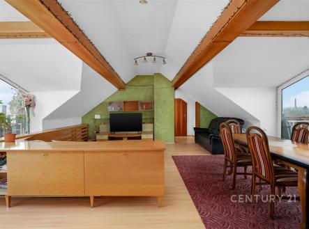 Prostorný obývací pokoj s parketovou podlahou, velkými okny a dřevěnými detaily, nabízí moderní a světlé prostředí pro pohodlné bydlení. | Prodej bytu, 3+kk, 127 m²