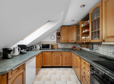 Podkrovní kuchyň s dřevěnými skříňkami, dlažbou a velkým střešním oknem. Moderní spotřebiče a dostatek úložného prostoru. | Prodej bytu, 3+kk, 127 m²