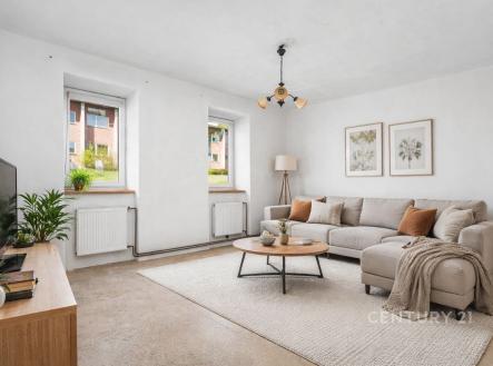 Světlý obývací pokoj s moderními betonovými podlahami, velkými okny a světlým nábytkem, vytvářejícími příjemnou atmosféru. | Prodej - dům/vila, 78 m²