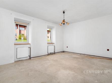 Prázdná světlá místnost, betonová podlaha, bílá výmalba, dvě okna s výhledem na zeleň, příprava na rekonstrukci, ideální pro modernizaci | Prodej - dům/vila, 78 m²