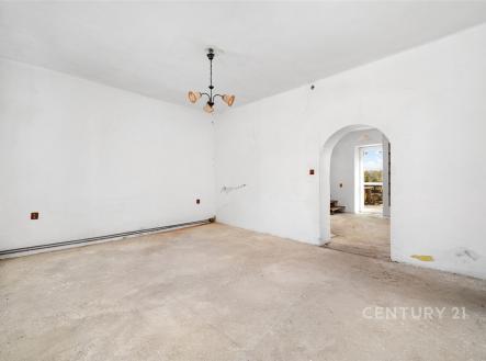 Prázdný obývací pokoj s neutrálními bílými stěnami, podlahou připravenou k úpravě a arkýřem. Interiér vhodný k rekonstrukci. | Prodej - dům/vila, 78 m²