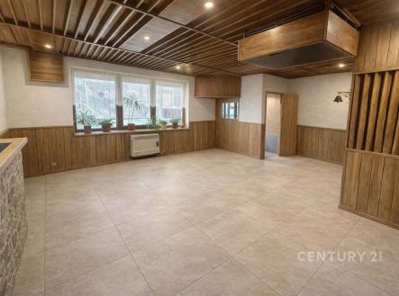 Světlý obývací pokoj s dlažbou, dřevěným obložením a velkými okny, nabízí moderní design a prostorný interiér. | Prodej - dům/vila, 170 m²