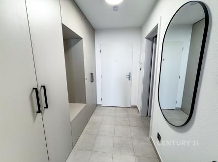 Úzká předsíň s dlažbou a vestavěnými skříněmi. Moderní interiér s velkým zrcadlem na stěně, bílé dveře a světlé barvy. | Pronájem bytu, 1+kk, 36 m²