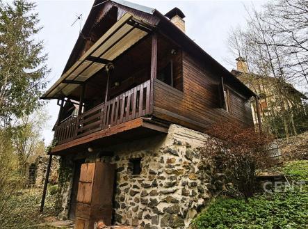 Dřevěná chata s kamennou podezdívkou, obklopená lesem, nabízí klidné prostředí. Rustikální design s balkónem a výhledem na přírodu. | Prodej - chata/rekreační objekt, 50 m²