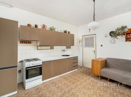 Kuchyňská linka s dlažbou a vestavěnými skříněmi, vedle gauče. Světlý prostor nabízí vintage design a praktické uspořádání. | Prodej - dům/vila, 215 m²