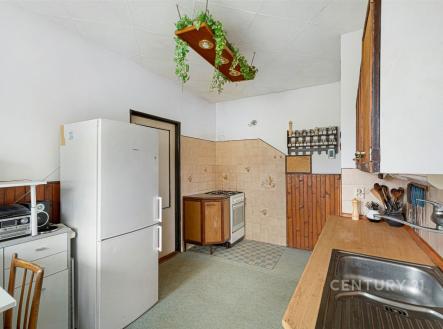 Kuchyň s retro dlažbou, dřevěným obložením a plynovým sporákem, vybavená lednicí a vestavěnými skříněmi, nabízí útulné bydlení. | Prodej - dům/vila, 215 m²