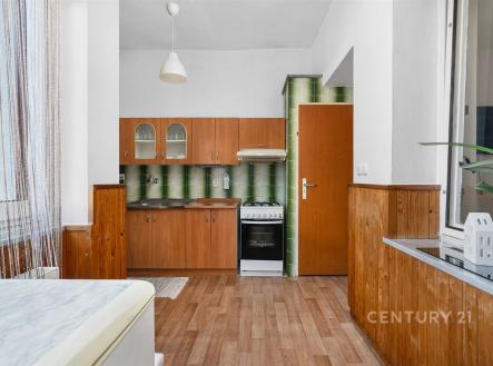 Kuchyň s dřevěnými skříňkami, parketovou podlahou a retro obkladem zelené barvy, vybavená plynovým sporákem a velkým oknem. | Prodej - dům/vila, 84 m²