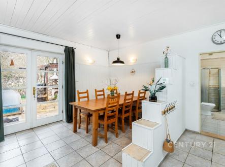 Jídelna s dlažbou, velkými okny a moderním osvětlením. Světlý prostor nabízí přístup na terasu, ideální pro rodinné večeře. | Prodej - dům/vila, 217 m²