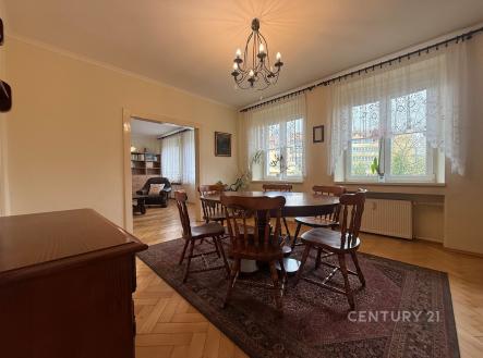 Jídelna s parketovou podlahou a velkými okny, klasický styl, dřevěný nábytek a lustr dodávají místnosti elegantní atmosféru. | Prodej bytu, 5+1, 110 m²