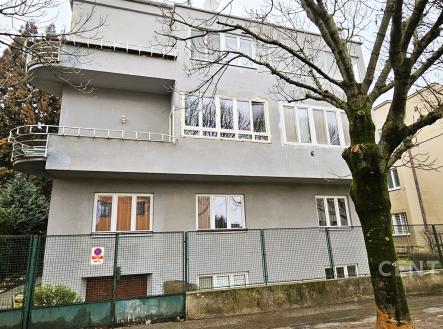 Fasáda vily s velkými okny a moderním designem, rekonstruovaný exteriér, stromy lemující ulici pro klidné okolí. | Prodej bytu, 3+1, 80 m²