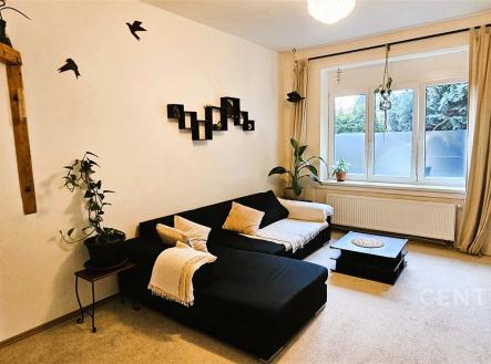 Světlý obývací pokoj s moderní výzdobou, kobercovou podlahou, velkými okny a minimalistickým nábytkem vytváří útulný prostor pro relaxaci. | Prodej bytu, 3+1, 80 m²