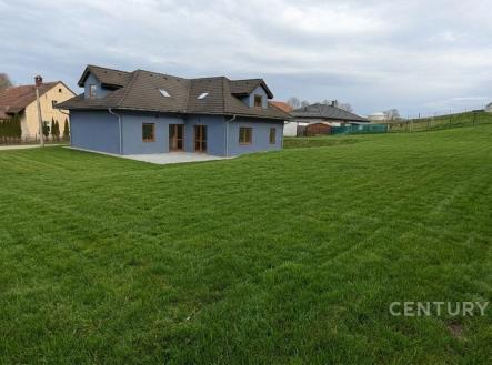 Rozlehlá zahrada s trávníkem a moderním rodinným domem v pozadí, dřevěná terasa, šikmá střecha, klidná lokalita. | Prodej - dům/vila, 320 m²