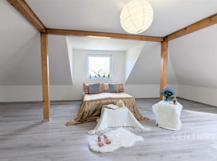 Podkrovní ložnice s moderními dřevěnými trámy, světlou parketovou podlahou a velkým oknem poskytujícím dostatek přirozeného světla. | Prodej - dům/vila, 320 m²