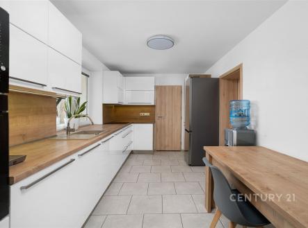 Moderní kuchyň s dlažbou, vestavěnými spotřebiči a dřevěnými pracovními deskami. Světlý prostor s elegantními bílými skříňkami. | Prodej - dům/vila, 190 m²