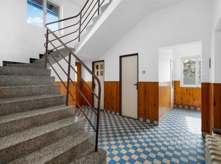Vstupní hala s dlažbou, dřevěným obložením a schodištěm. Světlý prostor s moderní rekonstrukcí a velkými okny. | Prodej - dům/vila, 160 m²