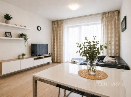 Světlý obývací pokoj s parketovou podlahou, velkými okny a moderním nábytkem. Clean lines a minimalistický design vytváří elegantní atmosféru. | Prodej bytu, 2+kk, 54 m²