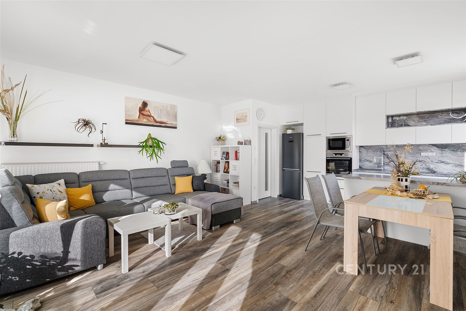 Světlý obývací pokoj s moderní kuchyní, dřevěná podlaha, velká okna, stylový nábytek, otevřený prostor, moderní design, přírodní dekorace