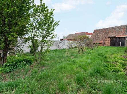 Zahrada se stromy, travnatá plocha a cihlová stavba, ideální pro rekonstrukci nebo výstavbu, klidná lokalita. | Prodej - pozemek pro bydlení, 1 147 m²