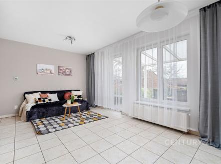 Světlý obývací pokoj s dlažbou, velkými okny a moderním vybavením, ideální pro rodinný život. | Prodej - dům/vila, 90 m²