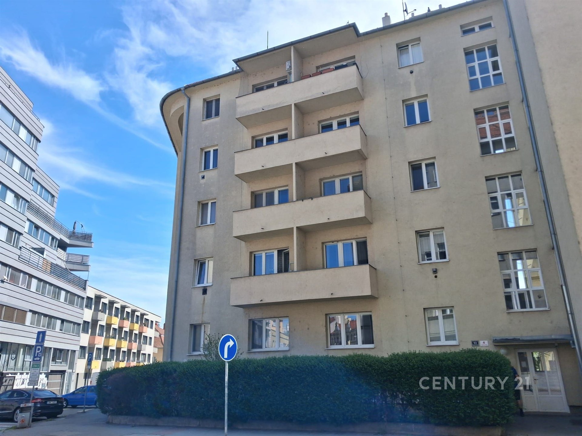 Fasáda bytového domu s moderním vzhledem, renovovaná okna a balkony, umístěná v klidné městské části s dostupností veřejné dopravy.