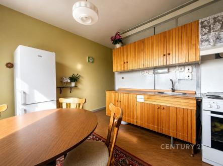 Kuchyň s dřevěnou linkou, kulatým stolem a židlemi, linoleová podlaha, světlý prostor. | Prodej bytu, 2+1, 60 m²