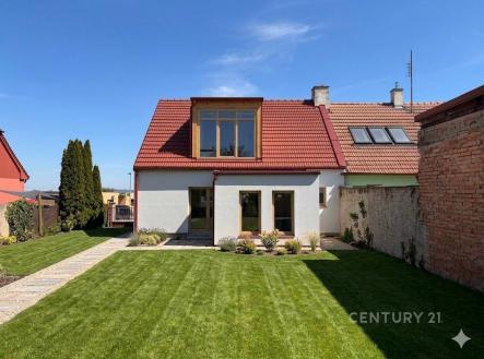 Zahrada s upraveným trávníkem, cihlovým plotem a moderní renovovanou fasádou domu, jsou zde také velká okna a červená střešní krytina | Pronájem - dům/vila, 128 m²
