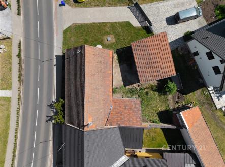 Letecký pohled na rodinný dům s červenou střešní krytinou, dlážděná příjezdová cesta a udržovaná zahrada, klidná lokalita blízko centra. | Prodej - dům/vila, 103 m²