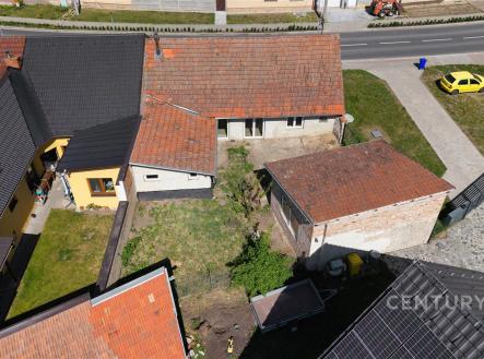 Venkovní prostor s trávníkem, dvěma domy se šikmými střechami a přístřeškem, dlážděná příjezdová zóna, klidná rezidenční lokalita. | Prodej - dům/vila, 103 m²