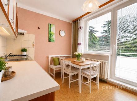 Světlá kuchyně s parketovou podlahou, velkými okny a moderním jídelním stolem nabízí útulný prostor pro rodinné setkání. | Prodej bytu, 1+1, 40 m²