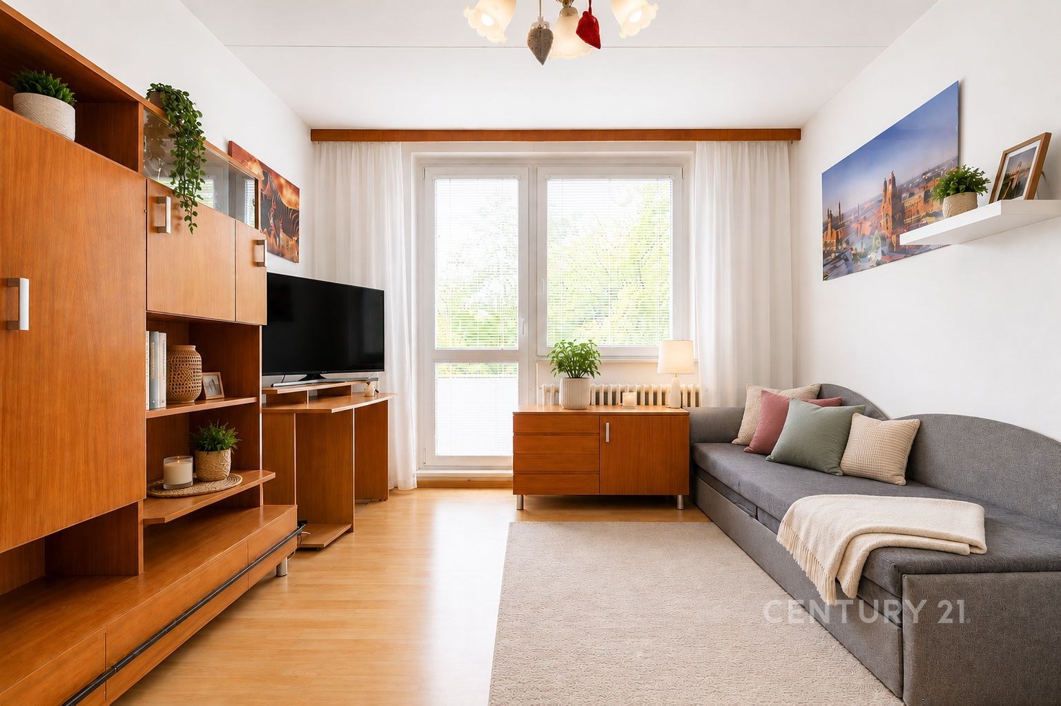 Světle zařízený obývací pokoj s parketovou podlahou, velkými okny a moderním nábytkem z dřeva, který dodává prostoru útulný a moderní vzhled.