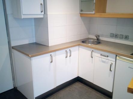 Moderní kuchyň s bílými skříňkami, dlažbou na podlaze a rohovým pracovním pultem, ideální pro malé prostory. | Pronájem bytu, 2+kk, 40 m²