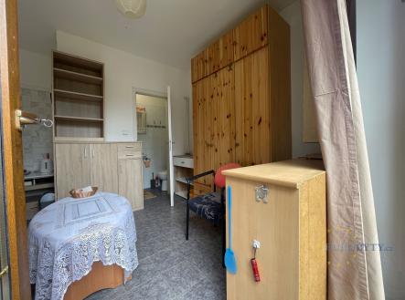 Jednolůžkový pokoj s dlažbou, vestavěné skříně z dřeva, světlý interiér s přístupem do koupelny, rustikální styl nábytku. | Pronájem bytu, garsoniéra, 12 m²