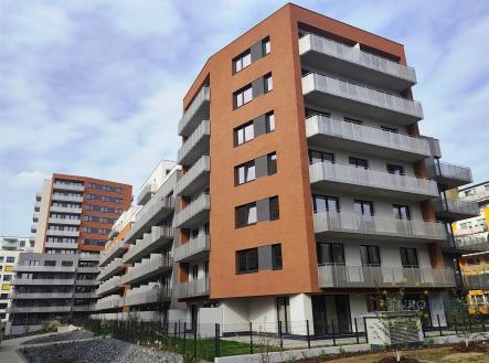 Moderní bytový dům s červenou a bílou fasádou, prostorné balkony, novostavba, v klidné lokalitě s upraveným okolím a zelení. | Pronájem bytu, 1+kk, 44 m²