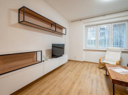 Světlý obývací pokoj s parketovou podlahou, moderním nábytkem a velkými okny, které zajišťují dostatek přirozeného světla. | Pronájem bytu, 1+kk, 29 m²