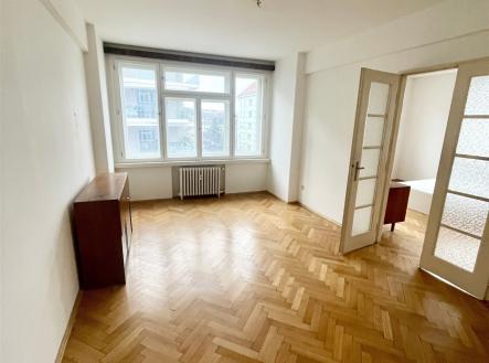 Prostorný obývací pokoj s parketovou podlahou, velkými okny a bílými stěnami, ideální pro moderní bydlení. | Pronájem bytu, 3+1, 92 m²