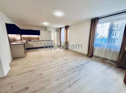 Prostorný obývací pokoj s moderní kuchyní a světlou parketovou podlahou, velká okna poskytují dostatek přirozeného světla. | Pronájem bytu, 2+kk, 55 m²