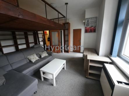 Obývací pokoj s moderním nábytkem a parketovou podlahou nabízí vestavěné police a velká okna zajišťující světlost prostoru | Pronájem bytu, 1+kk, 40 m²