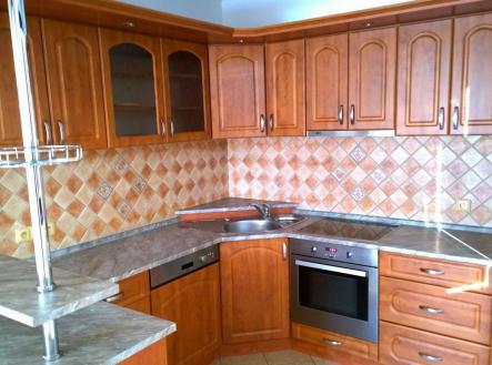 Kuchyň s dřevěnými skříňkami, moderními spotřebiči a dlažbou na stěnách, nabízí světlé prostředí a funkční prostor pro vaření. | Prodej - dům/vila, 290 m²