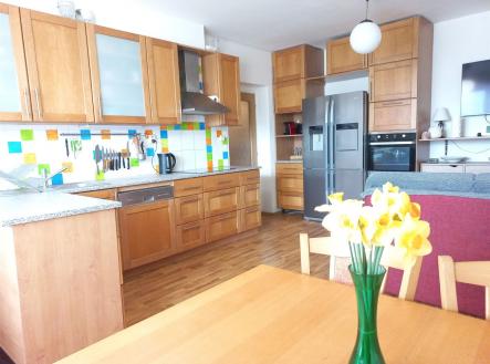 Kuchyň s dřevěnými skříňkami a parketovou podlahou, moderní spotřebiče a barevný obklad, prostorný a světlý interiér. | Prodej bytu, 3+kk, 73 m²