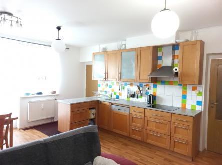 Prostorná kuchyň s parketovou podlahou nabízí moderní dřevěné skříňky a barevné obklady. Světlé prostředí dotvářejí velká okna a stylové osvětlení. | Prodej bytu, 3+kk, 73 m²
