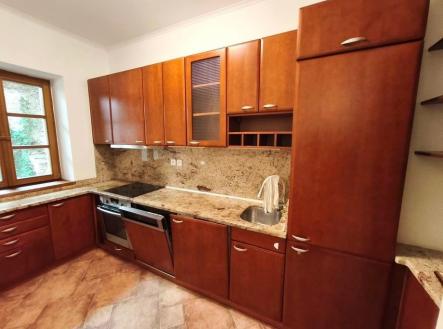 Kuchyň s dřevěnými skříněmi, dlažbou na podlaze a granitovou pracovní deskou. Světlá a moderní, ideální pro rekonstrukci. | Pronájem bytu, 4+1, 92 m²