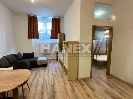 Obývací pokoj s dřevěnou podlahou, velkými okny a moderním nábytkem nabízí světlý prostor, ideální pro pohodlné bydlení. | Prodej bytu, atypický, 47 m²