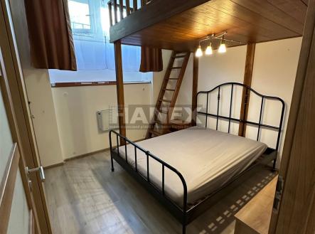 Malá ložnice s dřevěným patrem, kovovou postelí a parketovou podlahou. Světlé provedení, ideální pro úsporu místa. | Prodej bytu, 2+1, 47 m²