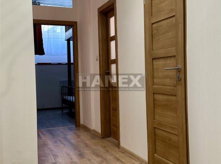 Chodba s dřevěnými dveřmi a laminátovou podlahou, moderní a světlá, ideální vstup do rekonstruovaného bytu. | Prodej bytu, 2+1, 47 m²